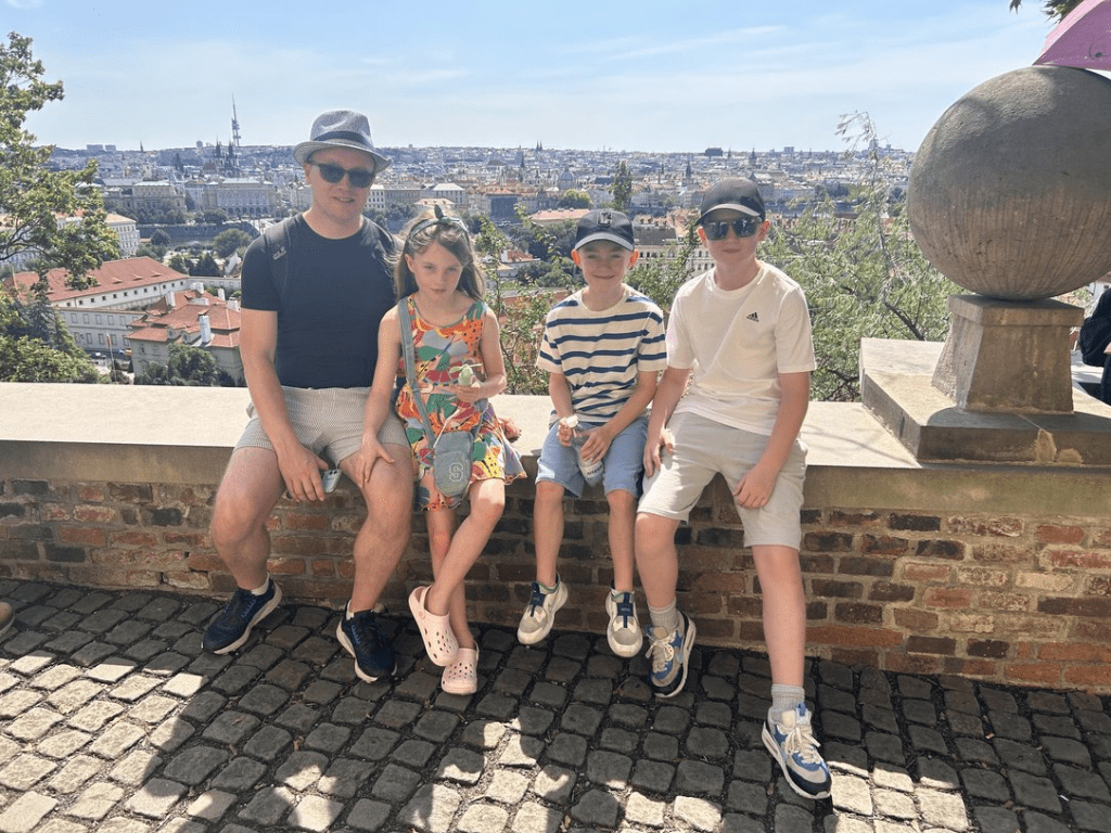 The Murtagh family rest on the walls of Prague Castle with the city skyline in the distance